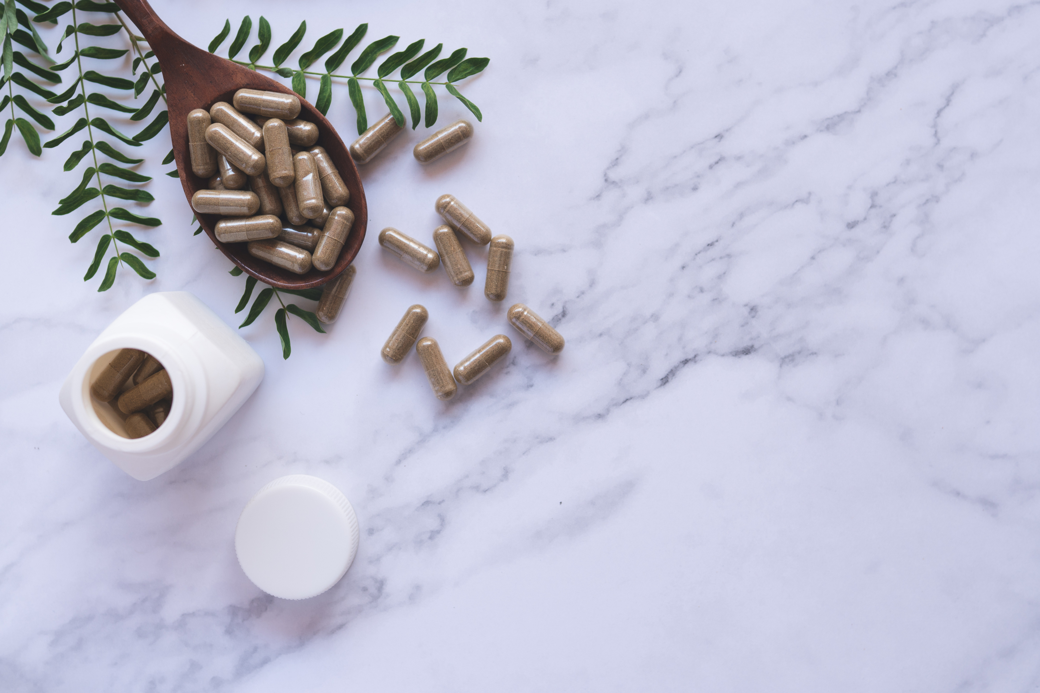 Herbal Capsules and Bottle on Marble Background